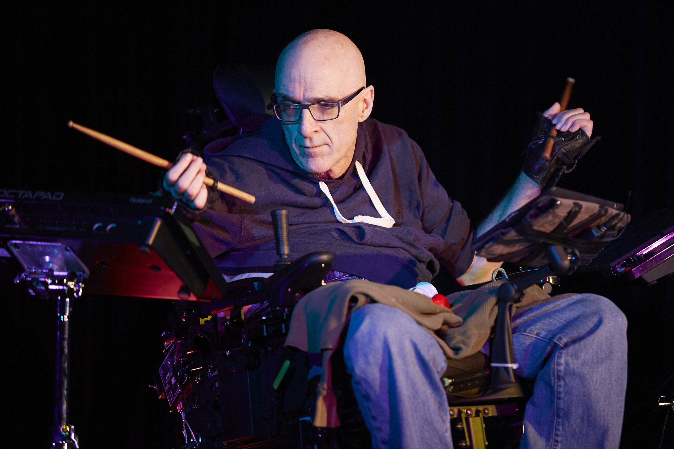 Production Photo from Re-calculating — An actor playing drums in a wheelchair