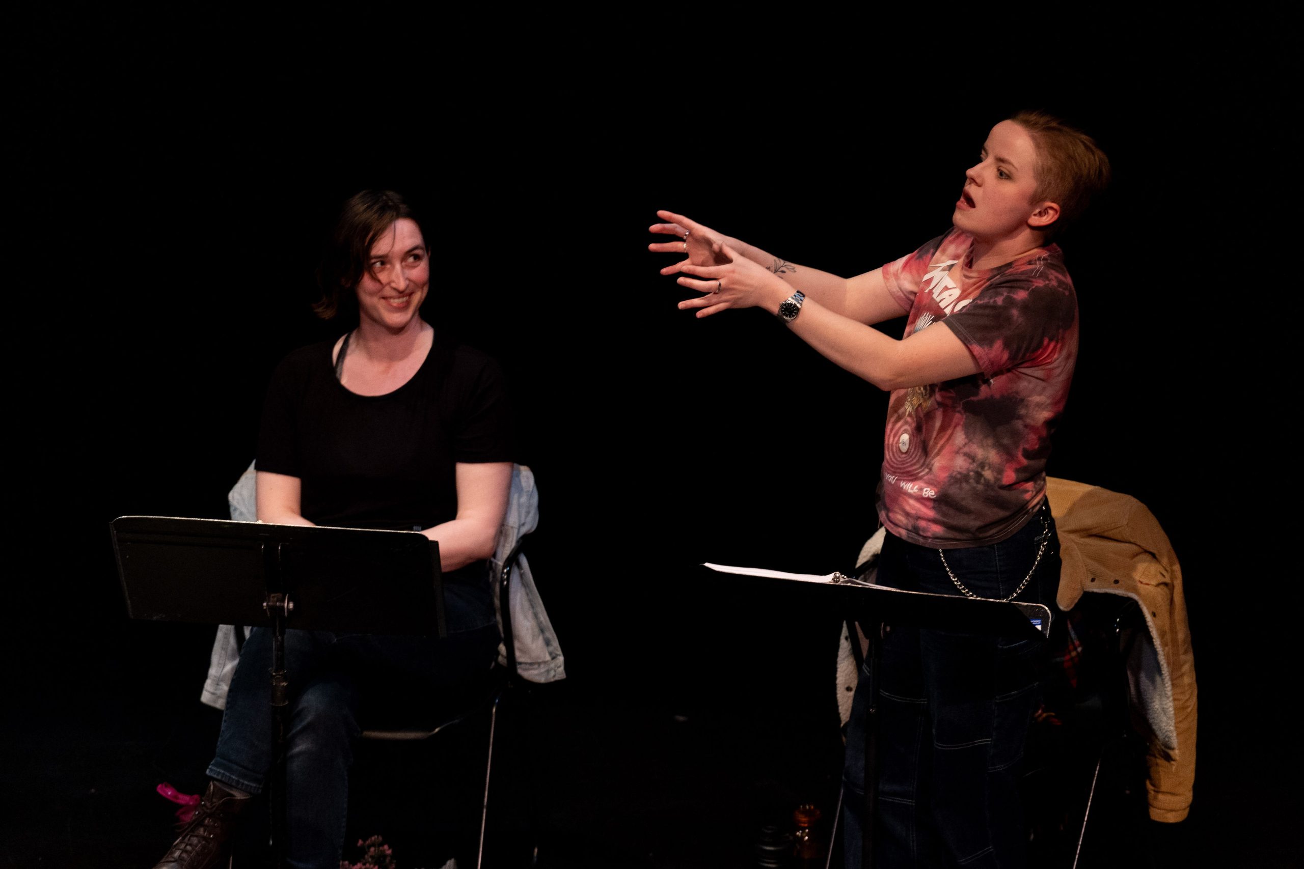 Staged Reading Photo from Vascular Necrosis - An actor imitating a zombie, another actor is sitting and smiling at them.