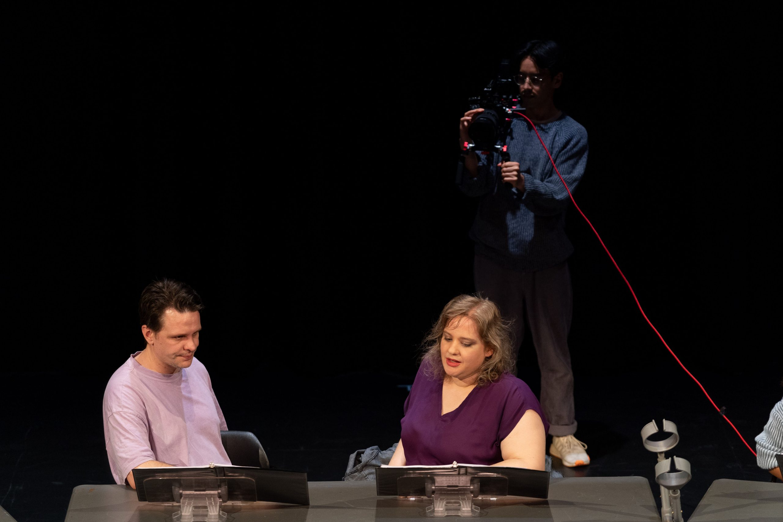 Staged Reading Photo from Saturday Nights At Axles - Two actors talk while the third films them with a camera.