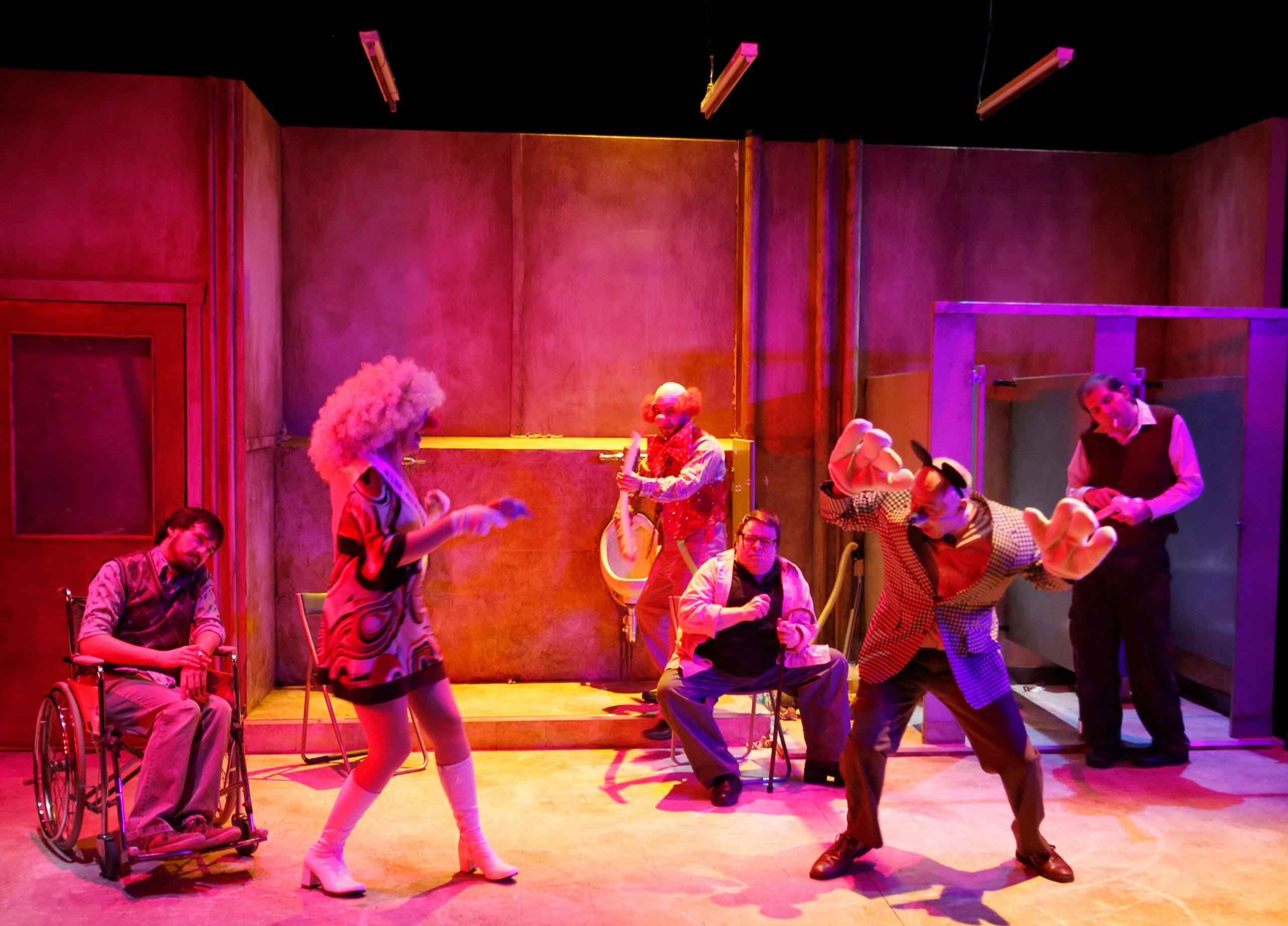 Production Photo from Creeps - A pink and orange-lit stage with the full cast of Creeps present. One of the performers is dressed as a clown, the other as a mouse.