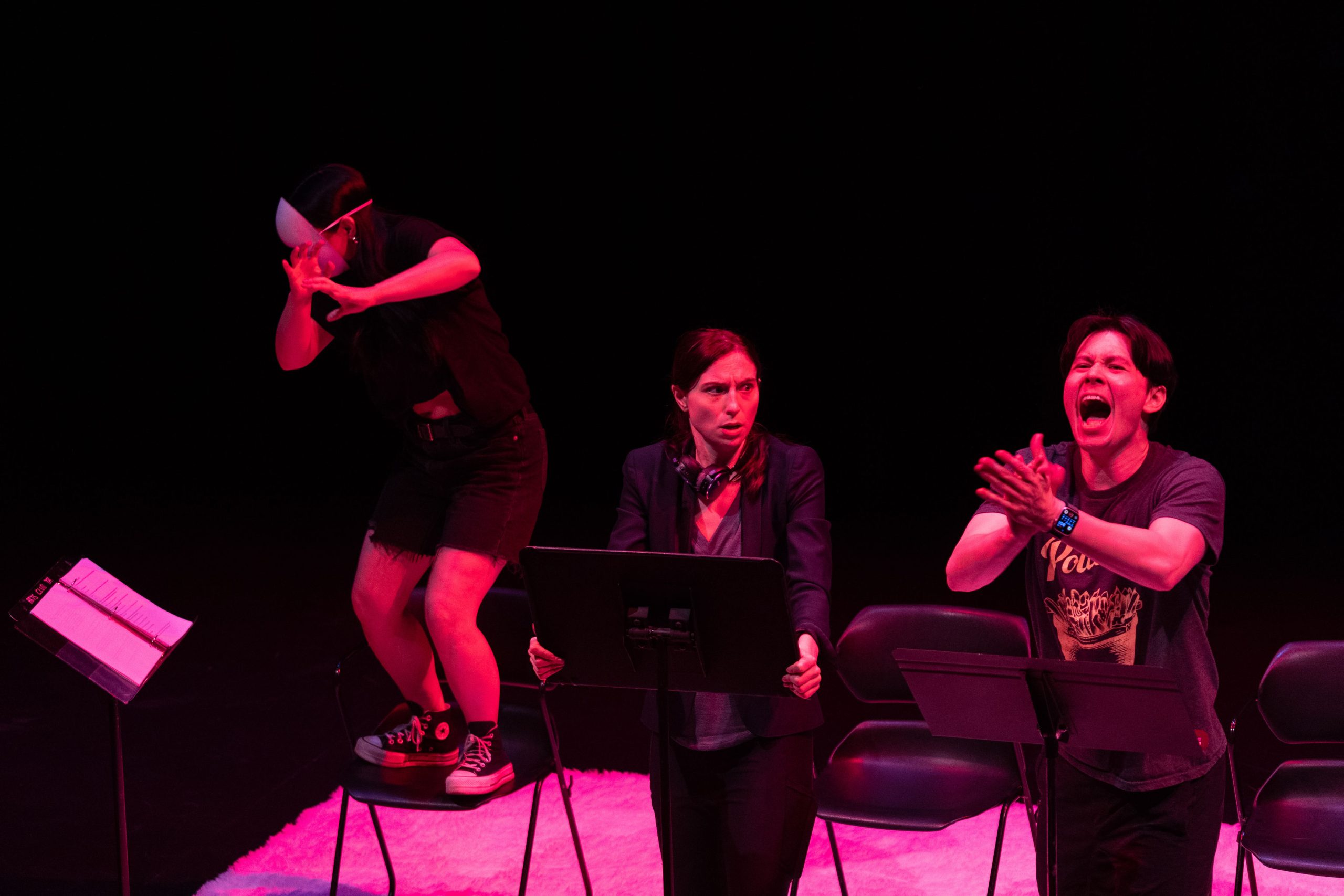 Staged Reading Photo from Faye's Room - An actor angrily claps, making another actor in a mask flinch away. The third actor looks horrified.