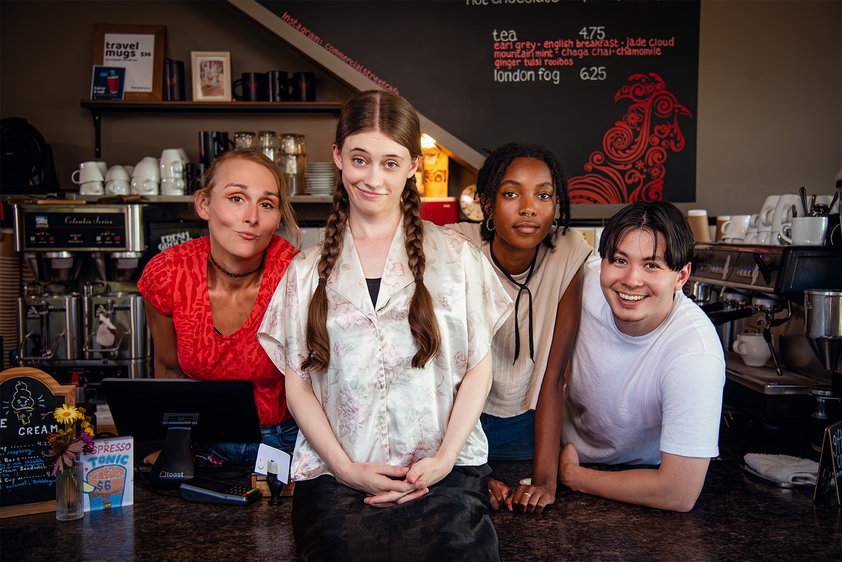 Promotional Photo of Faye's Room - The cast smiling at camera in a café