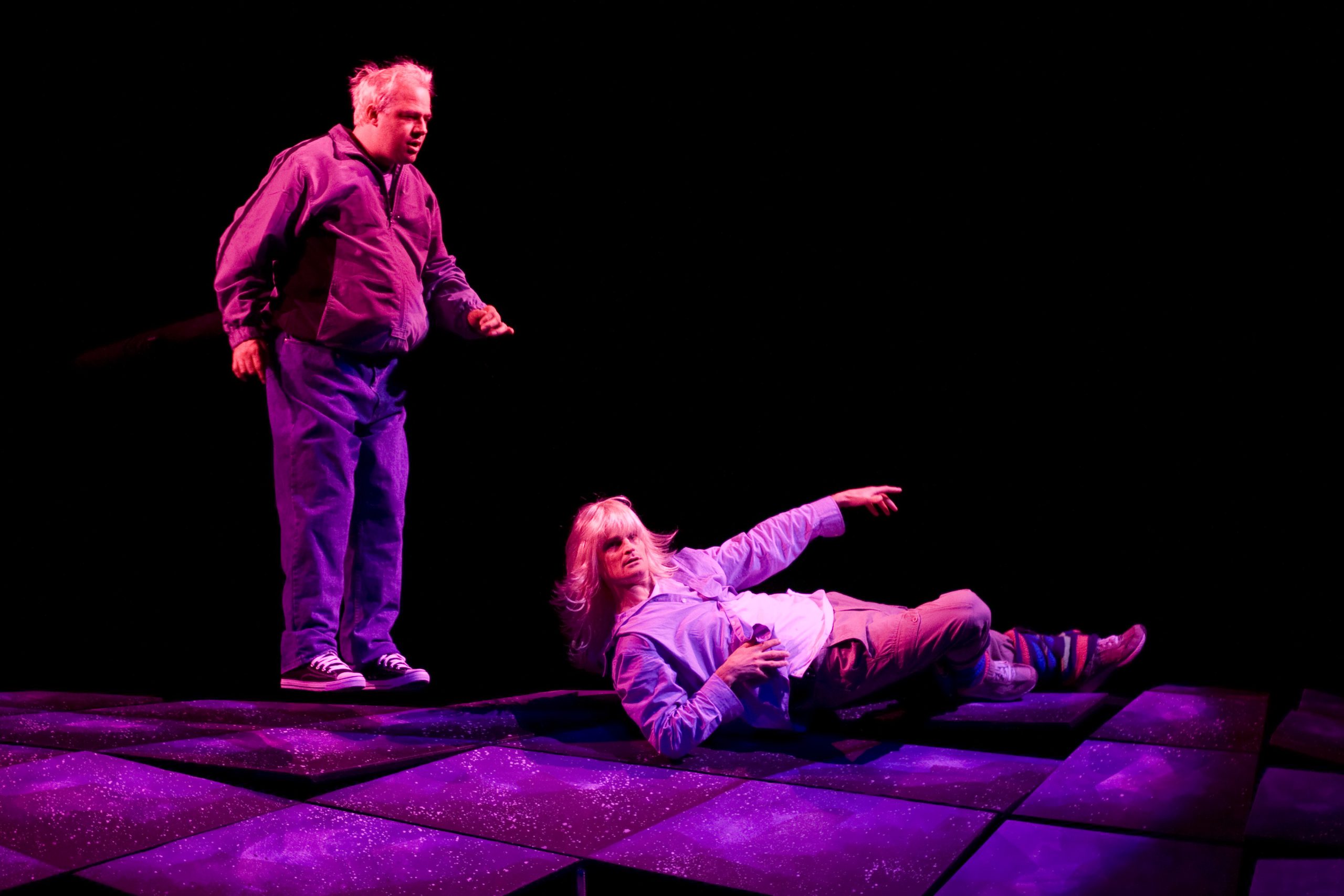 Production Photo from Skydive - Two actors, one standing, the other laying on the ground posing.
