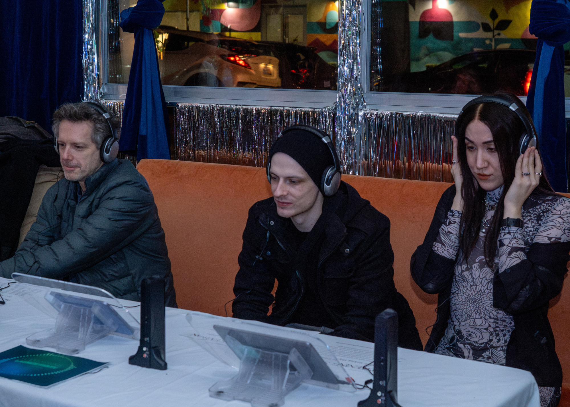 Photo from Release Party - three guests listening to Waveforms on headphones.