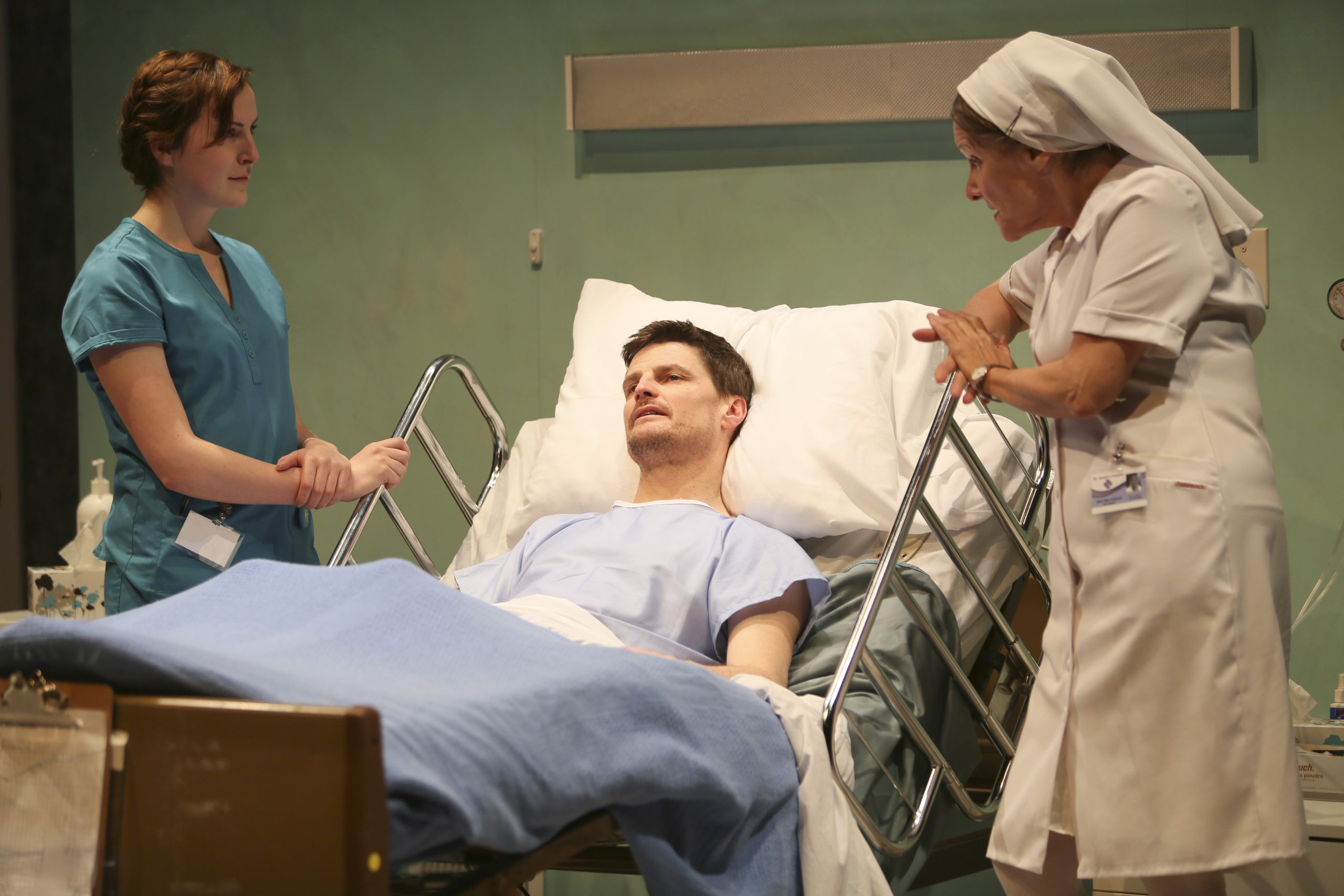 Production Photo from Whose Life is it Anyway? — Three actors, one in a hospital bed, the others a doctor and nurse.