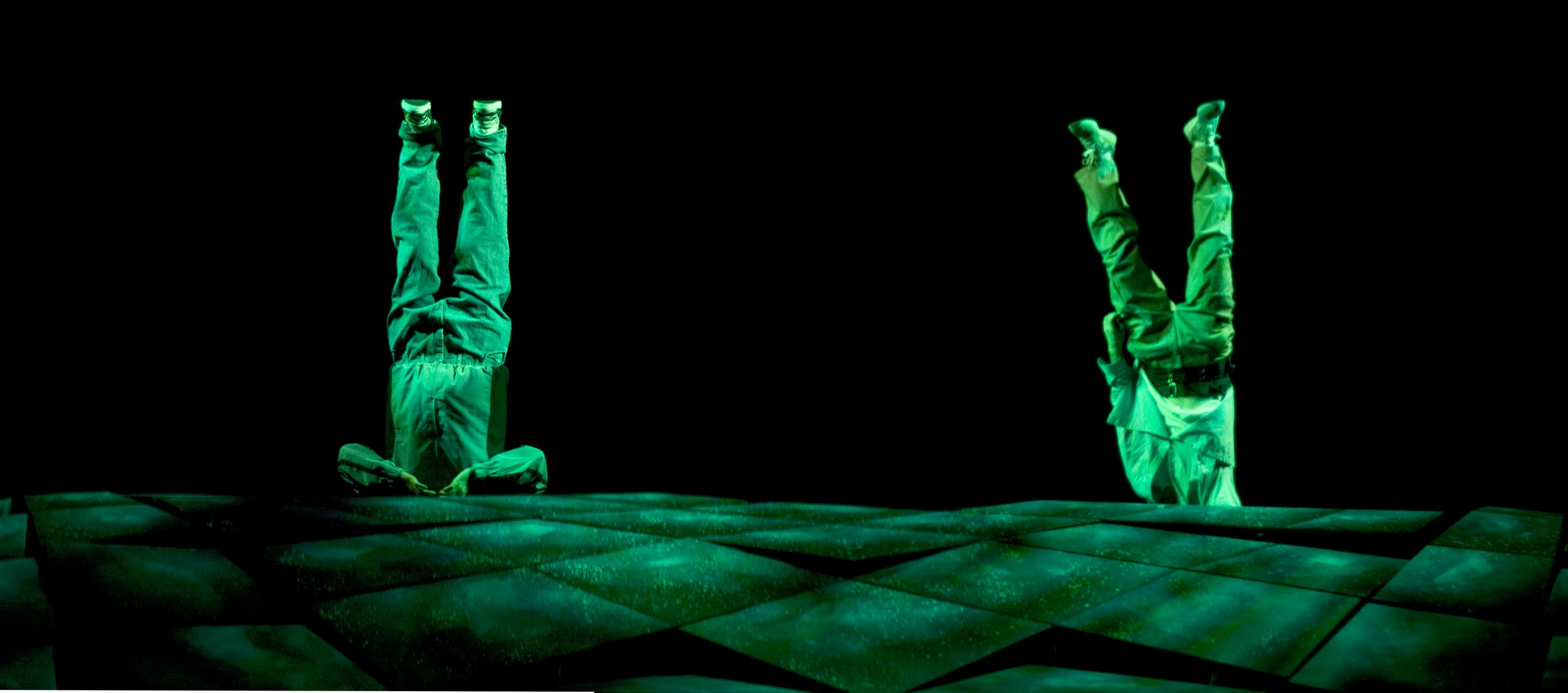 Production Photo from Skydive - Two men suspended upside down in green lighting.