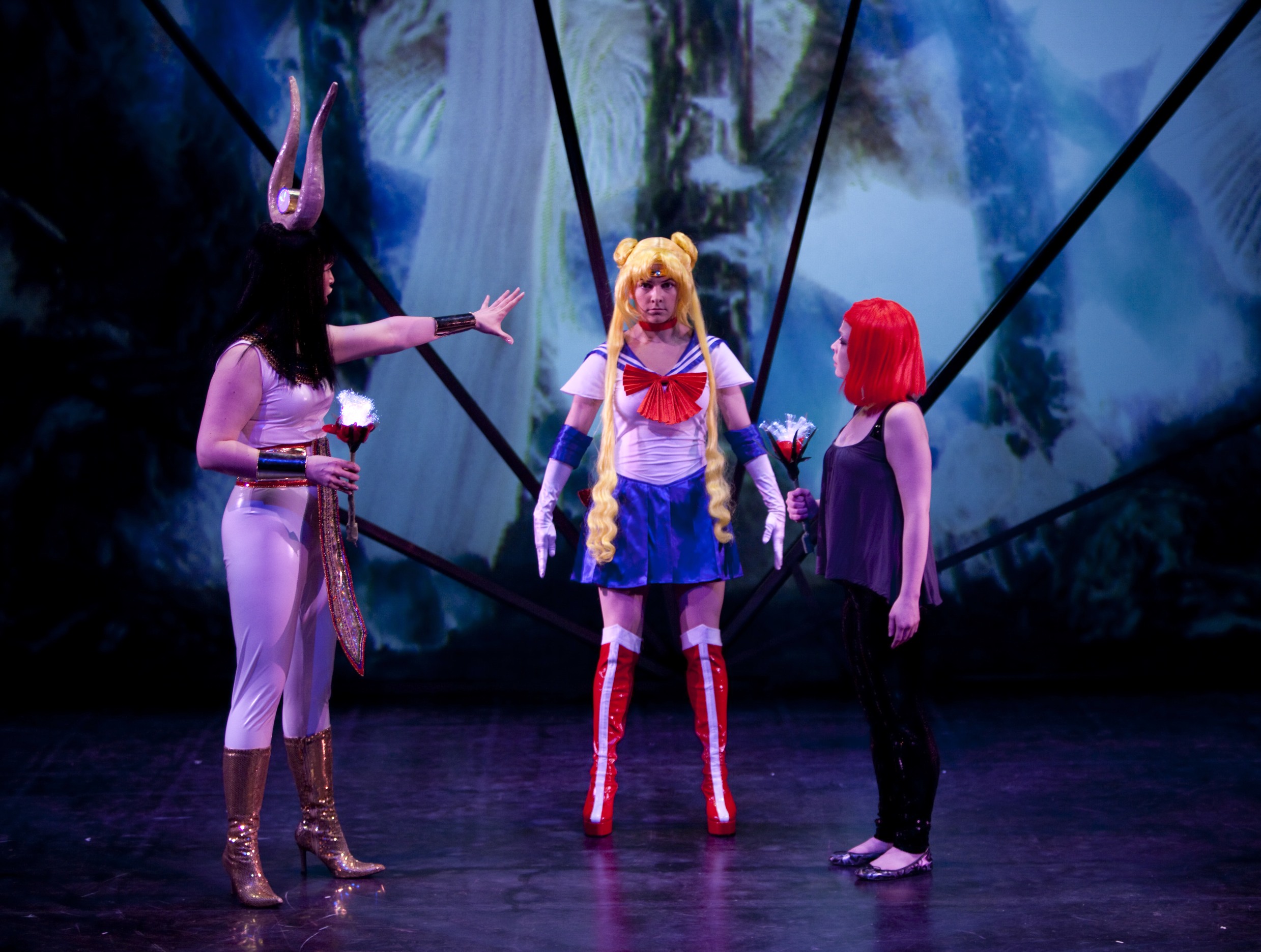 Production Photo from Spine - Three actors in anime-like costumes standing onstage.